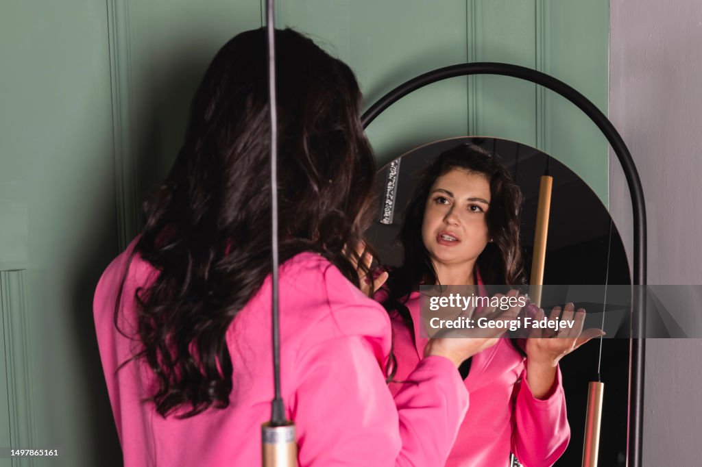 The girl is rehearsing a speech, talking to herself in the mirror.