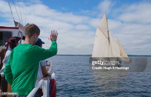 Boy waves at a passing yacht racing on the second day of the Richard Mille Cup for classic pre-1939 original and replica yachts on June 12, 2023 in...