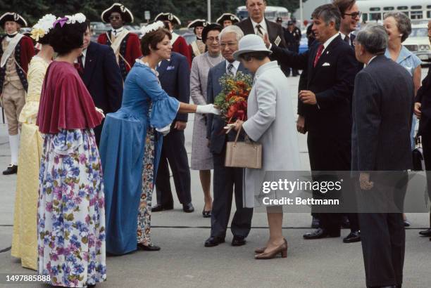 Emperor Hirohito and Empress Kojun of Japan are greeted by women in colonial dress as they arrive at Patrick Henry Airport in Williamsburg, Virginia,...