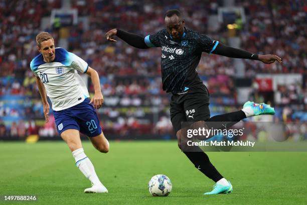 Usain Bolt of World XI crosses the ball under pressure from Michael Dawson of England during Soccer Aid for Unicef 2023 at Old Trafford on June 11,...