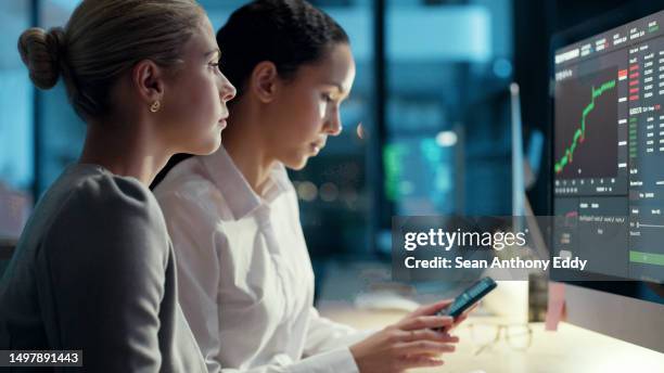 finance business women talking and looking at data, stats and a graph on a computer screen while working late at night in an office. female colleagues analysing a chart and trading stock online - statistics stock pictures, royalty-free photos & images