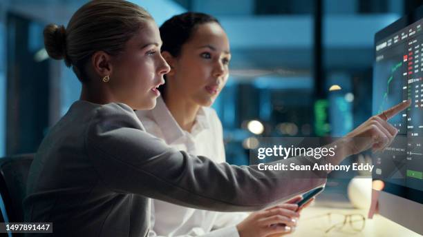 business, finance and economy professionals looking at the financial income and expense of the company on a computer screen. female traders working and collaborating overtime to meet a deadline - overdracht business mensen stockfoto's en -beelden