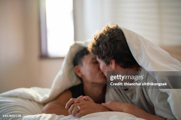 shot of affectionate love between gay couple at home kissing in bed. - asian lesbians kiss stock pictures, royalty-free photos & images