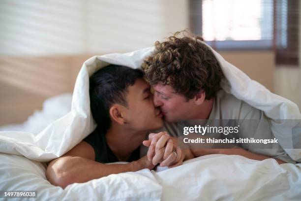 shot of romantic young gay couple having a good time together on bed. - asian lesbians kiss stock pictures, royalty-free photos & images