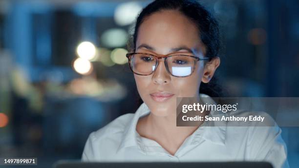 businesswoman working late on a computer in an office at night. confident, satisfied and hardworking young female entrepreneur smiling while feeling ambitious, proud and curious in a startup agency - bossy stock pictures, royalty-free photos & images