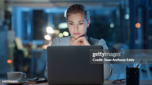 serious business executive working late night on laptop reading email or working on analytics report alone in modern office. corporate female manager or workaholic with a deadline working after hours - slow internet stock pictures, royalty-free photos & images