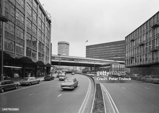 Signs for 'The Mayfair' club and 'Bullring Shopping Centre' on the pedestrian bridge above traffic on the Smallbrook Queensway in the city centre of...