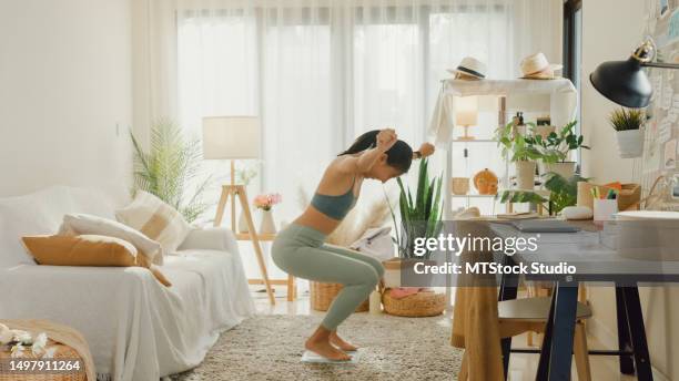 young asian athletic woman sitting on scales and excited over result of her weight loss diet in living room at home. diet and healthy weight loss. - fat asian woman stock pictures, royalty-free photos & images