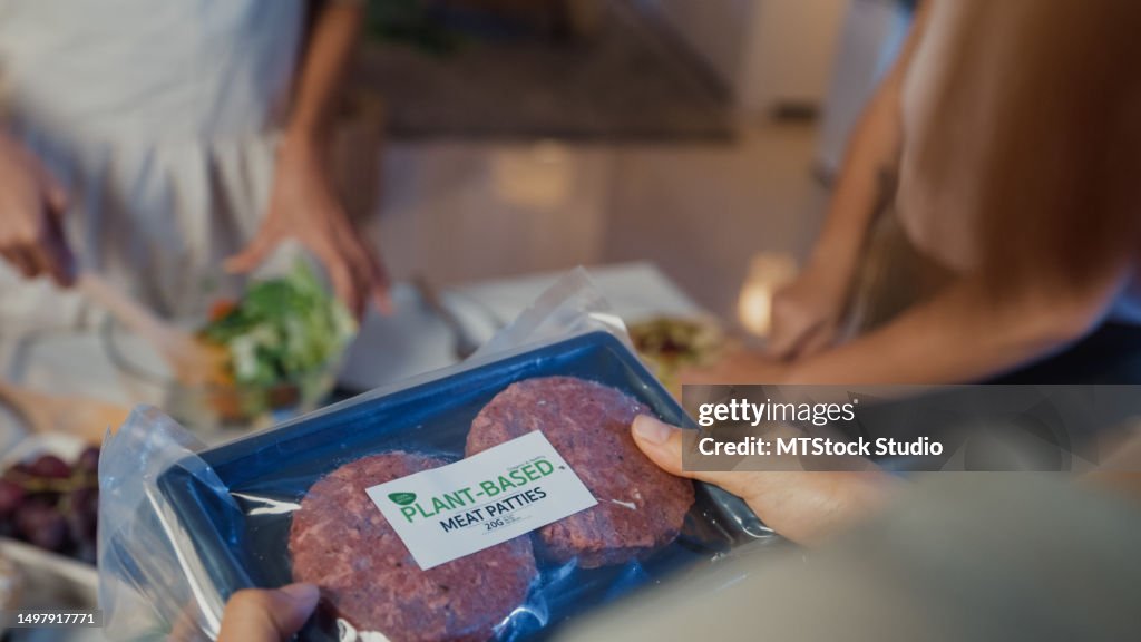 Nahaufnahme junger asiatischer Freundinnen, die mit einer Einkaufstüte aus dem Supermarkt kommen und nachts in der Küche zu Hause pflanzliche Mahlzeiten auspacken. Lebensstil, gesunde Ernährung, Essen, Genießen des natürlichen Lebenskonzepts.