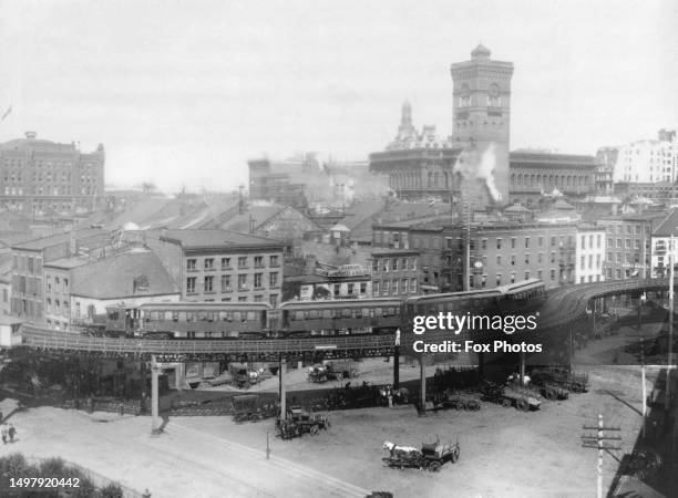 High-angle view showing horsecarts below an elevated section of the Third Avenue Line, a sign in the background reads 'DA Manson, Carpenter &...