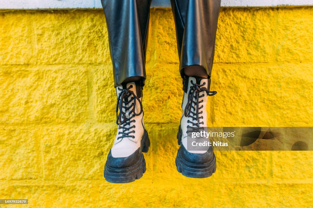 Black and white fashionable boots on a yellow wall