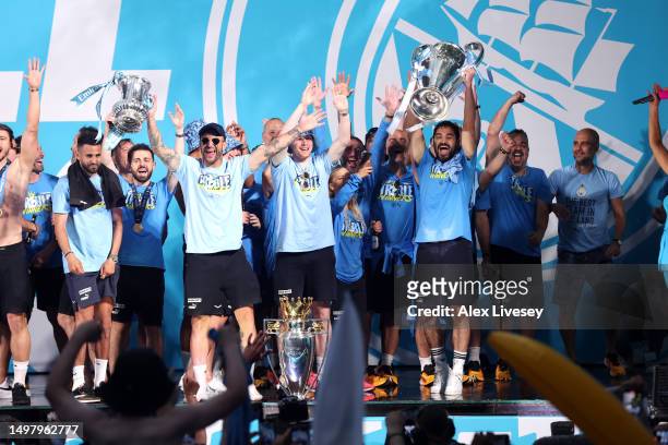 Kyle Walker lifts the FA Cup Trophy as Kevin De Bruyne celebrates with the Premier League Trophy and Ilkay Guendogan of Manchester City lifts the...