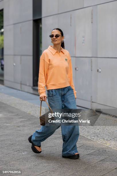 Anna Winter wears orange jumper Lacoste x sporty and rich, denim jeans Sourceunknown, platform sandals vic Matie, bag Louis Vuitton, sunglasses...