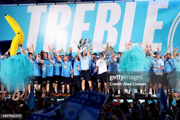 Erling Haaland lifts the UEFA Champions League Trophy as Ederson and Riyad Mahrez lift the Premier League Trophy on stage in St Peter's Square during...