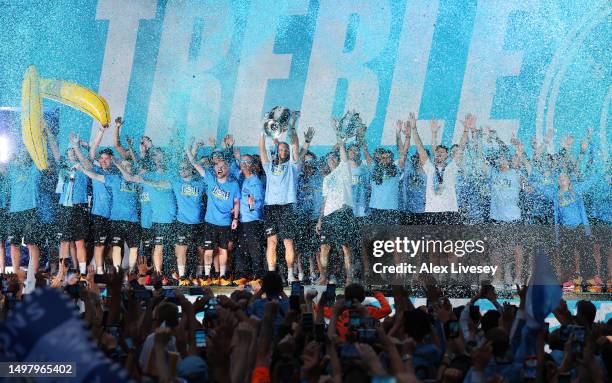 Erling Haaland lifts the UEFA Champions League Trophy as Ederson and Riyad Mahrez lift the Premier League Trophy on stage in St Peter's Square during...