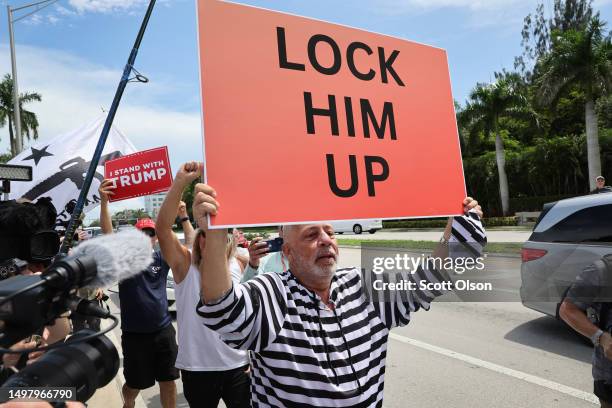 An anti-Trump demonstrator walks past supporters of former President Donald Trump as they wait for him to arrive at the Trump National Doral Miami...