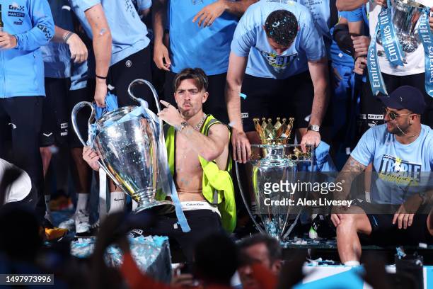 Jack Grealish of Manchester City celebrates with the UEFA Champions League Trophy and Premier League Trophy on stage in St Peter's Square during the...