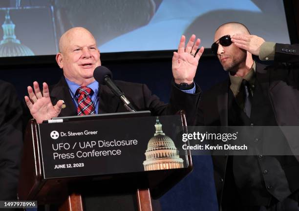 Air Force Lt. Col. Donald Heckert speaks about his UFO encounter as Army Private Steven Digna, Jr. Salutes him at a press event sponsored by Steven...