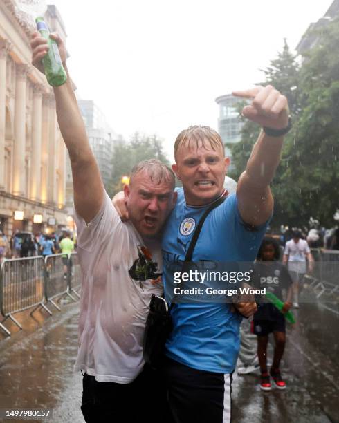 Manchester City fans celebrate in the rain during the Manchester City trophy parade on June 12, 2023 in Manchester, England.