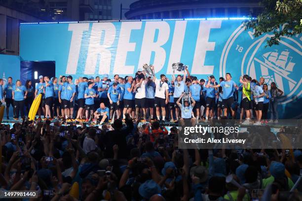 General view as players of Manchester City celebrates in front of the "Treble" banner on stage in St Peter's Square as Ederson and Ruben Dias lift...