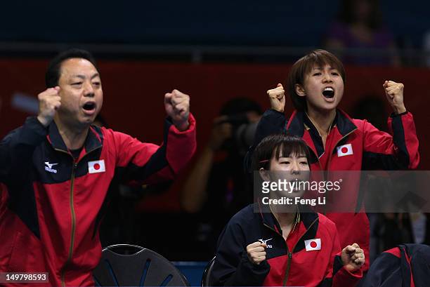 Kasumi Ishikawa and Sayaka Hirano of Japan celebrate with their coach Yasukazu Murakami during Women's Team Table Tennis quarterfinal match against...