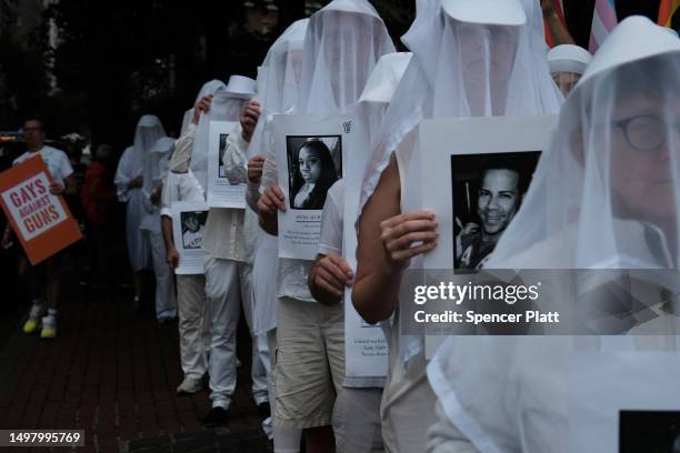 Members of the activist group Gays Against Guns hold pictures of the deceased during a silent vigil to mark seven years since the Pulse Nightclub...