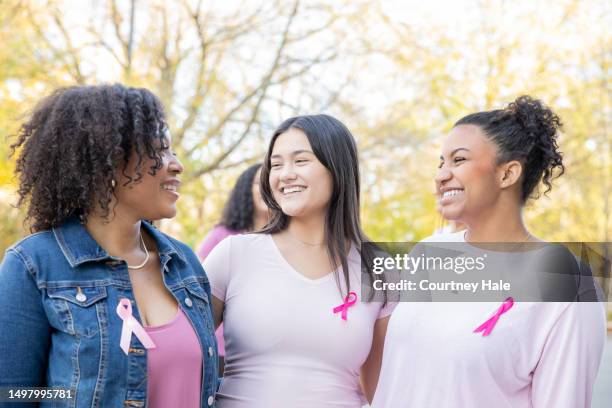 diverse group of young women smile while attending pink ribbon breast cancer charity event - bröstcancer bildbanksfoton och bilder