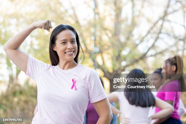 une belle femme mûre montre de la force en assistant à une activité de sensibilisation au cancer du sein et en portant un ruban rose - sensibilisation au cancer du sein photos et images de collection