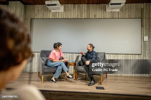 young woman interviewing a man at studio - media interview stock pictures, royalty-free photos & images