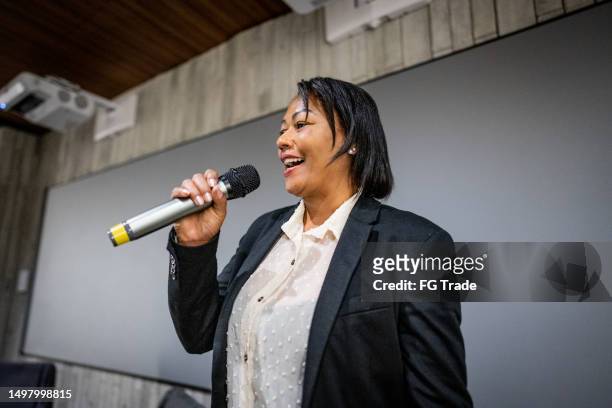 mature woman talking on microphone in a seminar - brazil training and press conference stock pictures, royalty-free photos & images
