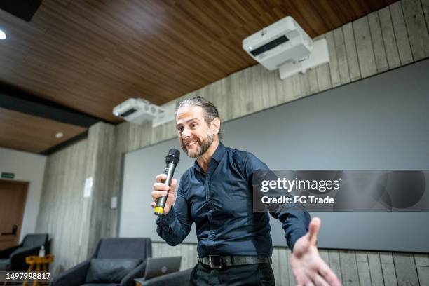 mature man talking on microphone in a seminar - founder stock pictures, royalty-free photos & images