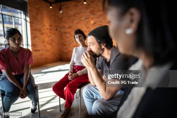 mid adult man talking during a therapy group - reünie sociaal stockfoto's en -beelden