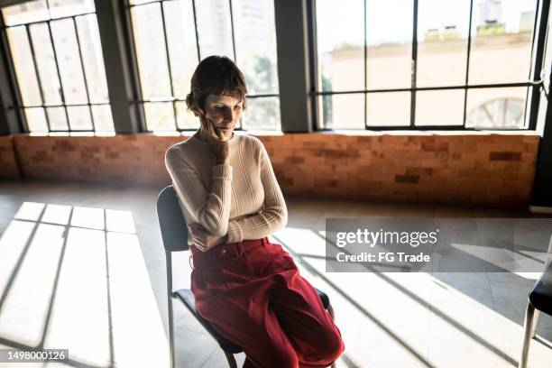 traurige reife frau, die auf einem stuhl in einer selbsthilfegruppe für psychische gesundheit wartet - vorurteil stock-fotos und bilder