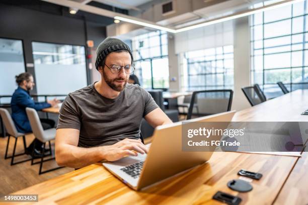 mid adult businessman working using laptop at office/coworking - casual clothing stock pictures, royalty-free photos & images