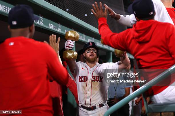 Christian Arroyo of the Boston Red Sox celebrates in the dugout with inflatable dumbbells after hitting a home run against the Colorado Rockies...