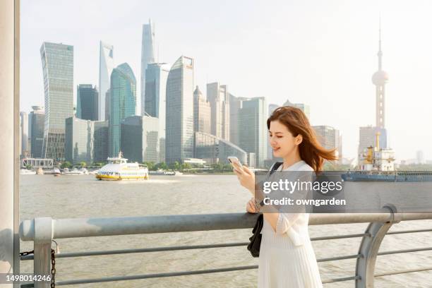 asian young businesswoman standing against contemporary financial skyscrapers - lujiazui imagens e fotografias de stock