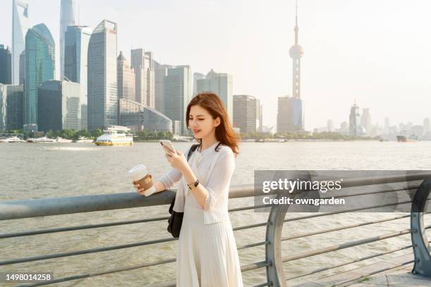 asian young businesswoman standing against contemporary financial skyscrapers - pudong stock-fotos und bilder