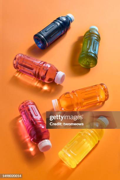 six bottles with multi-colored liquid on an orange background, still life. - oranje achtergrond stockfoto's en -beelden