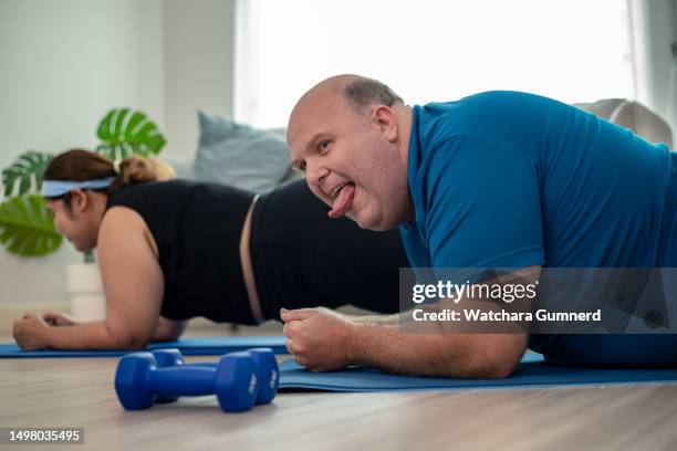 overweight man and woman doing exercise on mats in home - obesity trainer stock pictures, royalty-free photos & images