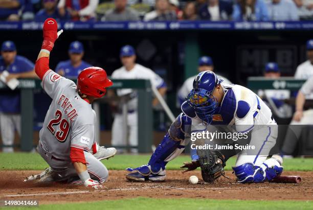 Friedl of the Cincinnati Reds slides into home plate as catcher Salvador Perez of the Kansas City Royals applies the tag during the 10th inning of...