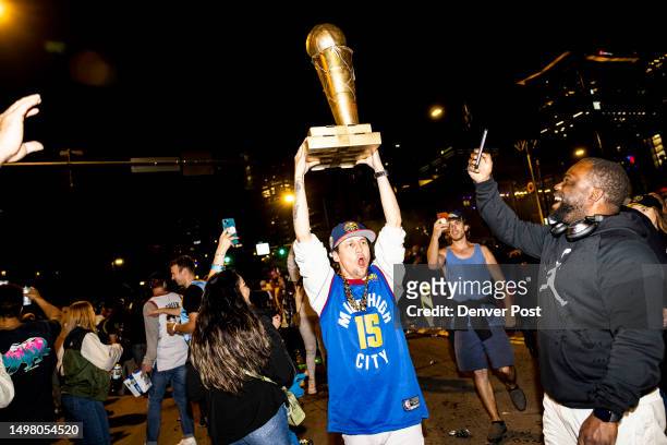 Denver Nuggets fan lifts a trophy in the air in the streets of downtown Denver, Colo., after winning Game 5 of the NBA Finals with the Denver Nuggets...