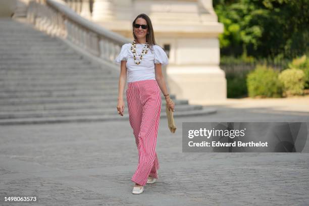 Alba Garavito Torre wears black sunglasses from Ray Ban, white pearls with gold chain pendant earrings, a white large pearls / black cordon / gold...