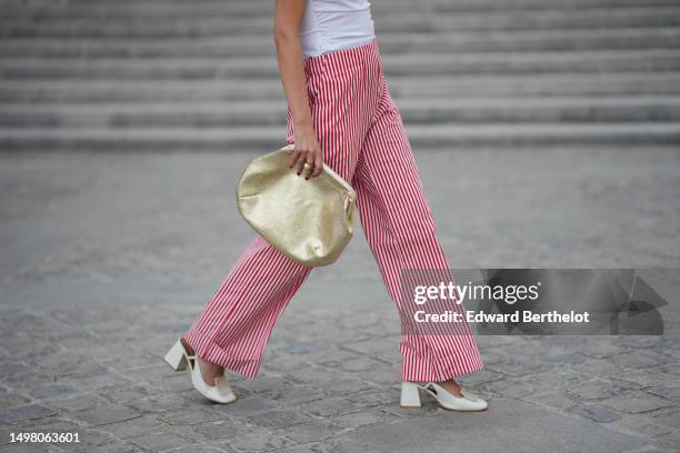 Alba Garavito Torre wears a white puffy short sleeves t-shirt, white and red striped print pattern flowing pants from Gingham Palace, gold bracelets,...