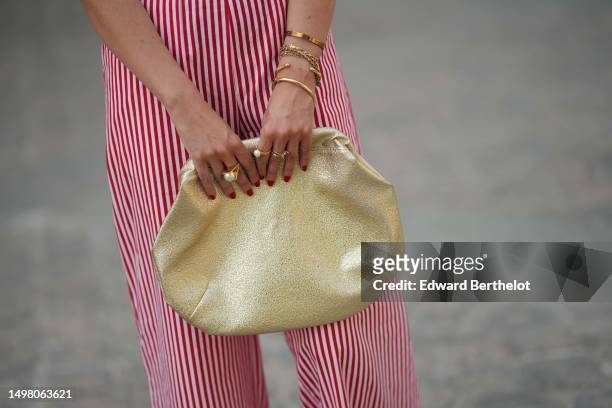 Alba Garavito Torre wears white and red striped print pattern flowing pants from Gingham Palace, gold bracelets, gold rings, a gold shiny varnished...