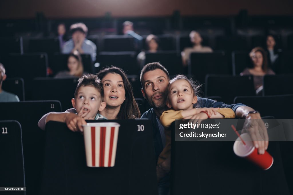 Familia joven viendo una proyección de película en el teatro.