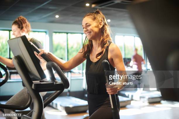 happy cross trainer - happy caucasian woman on elliptical trainer at gym stock pictures, royalty-free photos & images