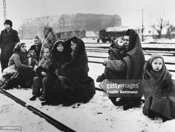 German refugees rest as they reach the outskirts of Berlin after fleeing Lodz in Poland, December 1945. The small group of women and children are...