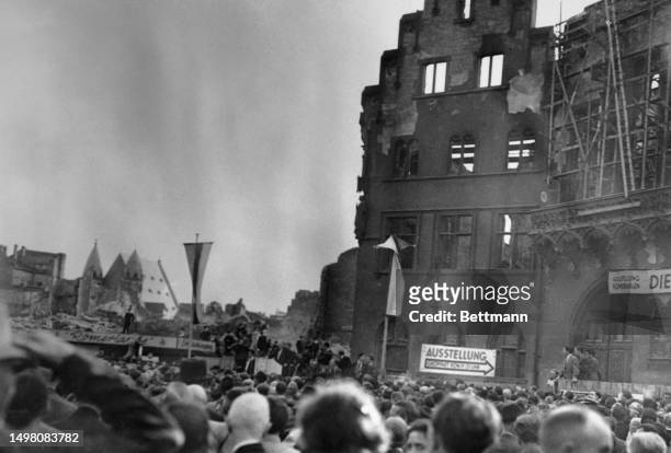 Ludwig Erhard is seen at a lectern in the background as he addresses an audience of more than 5,000 at an election rally in Frankfurt, August 9th...