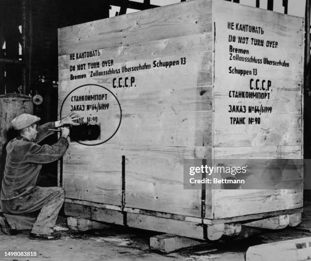German worker stencils a Russian address onto a crate filled with equipment from the FAG Kugelfischer factory in Schweinfurt which is being...