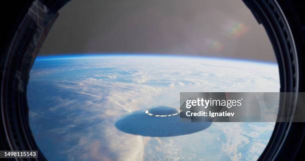 ufo gracefully glides over the surface of the earth - iss window stock pictures, royalty-free photos & images
